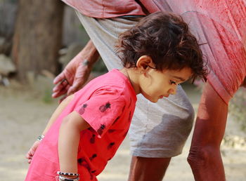 An indian-origin little boy with grandfather looking towards the ground, india.