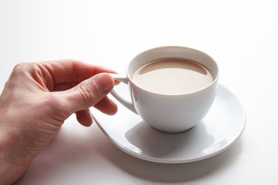 Midsection of person holding coffee cup against white background