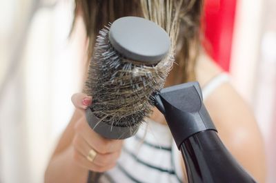 Close-up of woman drying hair with dryer