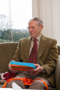 Midsection of man sitting on seat against window