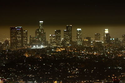 Illuminated buildings in city against sky at night