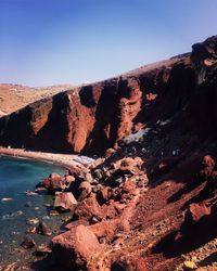 Scenic view of rocky mountains against clear sky red beach santorini