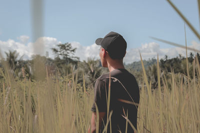 Rear view of man standing on field against sky