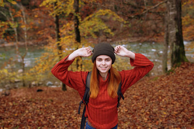 Happy young woman standing in park during autumn