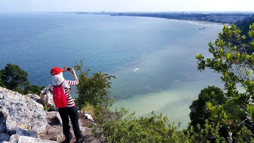 Rear view of woman photographing sea