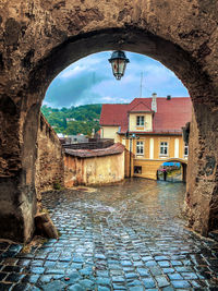 Wet street amidst buildings in city