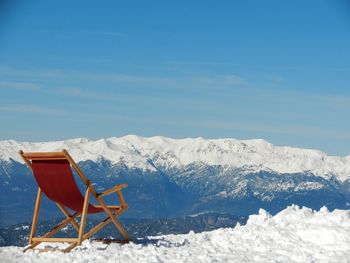 Chairs on snow covered mountain against sky
