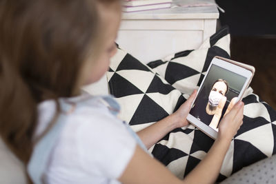 Girl using mobile phone on sofa at home