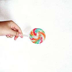 Cropped image of hand holding paper over white background