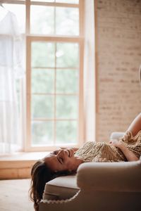 Smiling woman lying on sofa at home