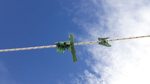 Low angle view of clothespins on rope against sky