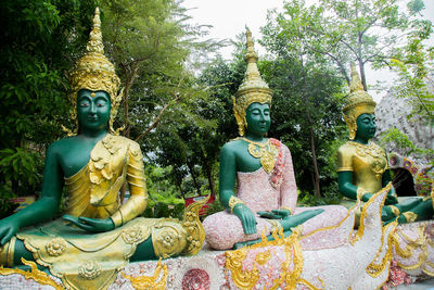 Buddha statue by trees against temple