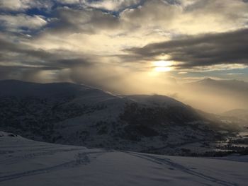 Scenic view of snowcapped mountains against dramatic sky