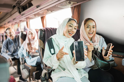 Portrait of smiling friends standing in bus