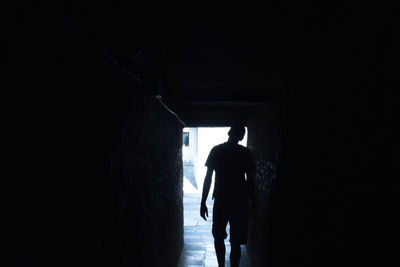 Rear view of silhouette man walking in tunnel