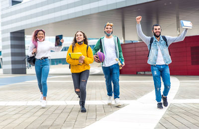 Cheerful friends carrying book outdoors