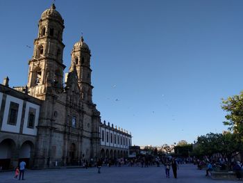 People at town square against clear blue sky