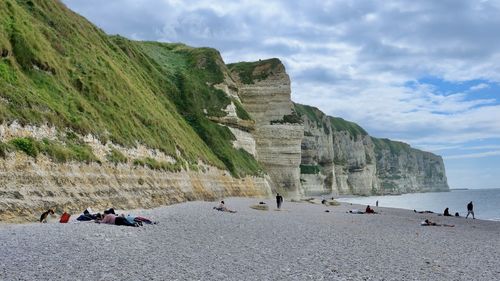 People on beach by mountain against sky