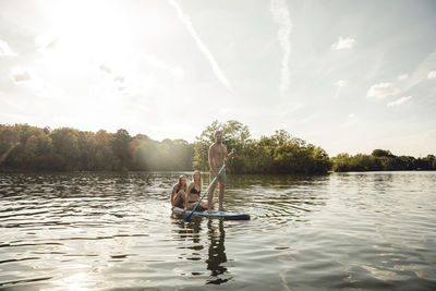 Friends enjoying summer on the lake, paddling on a paddleboard