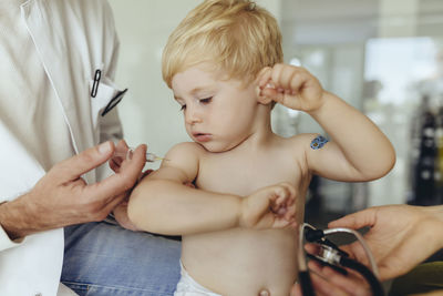 Pediatrician vaccinating toddler, injecting infant's arm