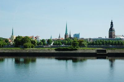 Scenic view of river by buildings against clear sky
