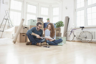 Couple surrounded by cardboard boxes sitting on floor