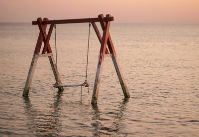 Lifeguard hut on sea against sky during sunset