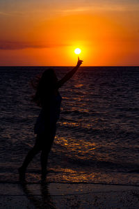 Silhouette person on beach against sky during sunset