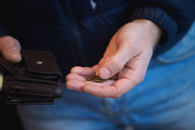 Midsection of man putting coins in wallet