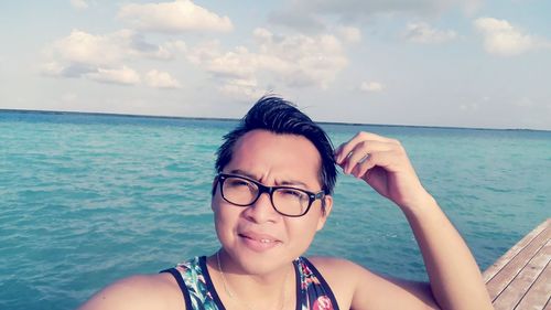 Portrait of smiling young man in sea against sky