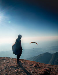 Rear view of man standing on mountain against sky