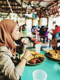 Midsection of woman having food in restaurant