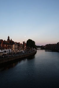 View of river and buildings against sky at sunset