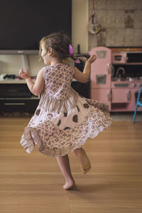 Joyous 4 yr old in tiered dress dancing barefoot on hardwood floor