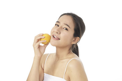 Portrait of woman holding apple against white background