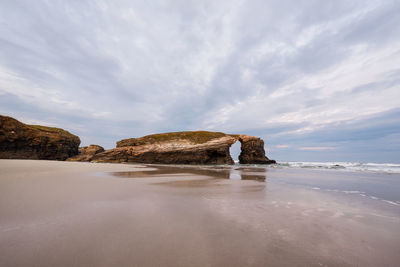 Rock formations on beach against sky