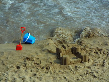 High angle view of sand castle with bucket and spade at beach