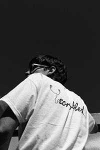 Rear view of man sitting against black background