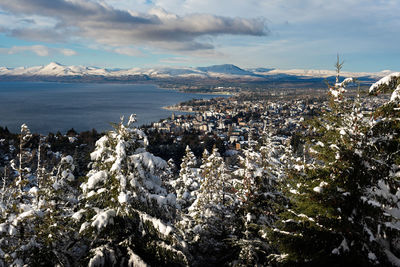 Aerial view of city by sea against sky