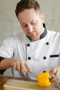 Close-up of male chef cutting yellow bell pepper at table