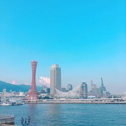 Sea and buildings in city against clear blue sky