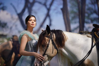 Portrait of a beautiful woman with a horse in the forest background.