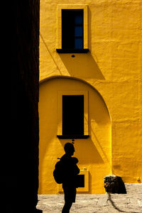 Silhouette man standing against yellow building