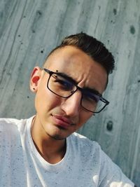 Portrait of young man wearing eyeglasses against wall