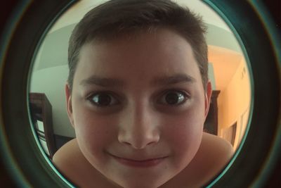 Close-up portrait of smiling boy seen through washing machine