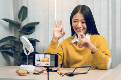 Young woman using mobile phone while sitting on table at home