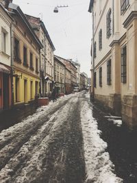Empty road amidst buildings during winter