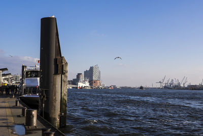 Buildings by sea against blue sky