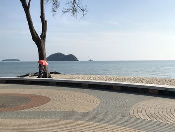 Man sitting by sea against sky