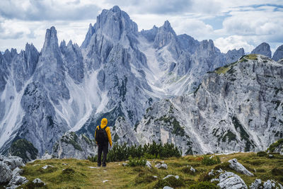 Man standing on rock with mountain range against sky